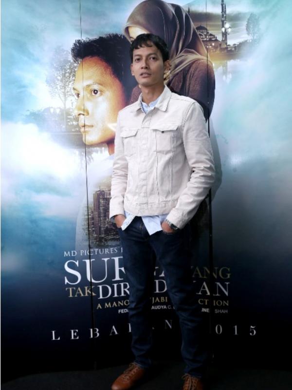 Fedi Nuril pemeran Andika berdiri di belakang poster film Surga Yang Tak Dirindukan. (Galih W Satria/Bintang.com)