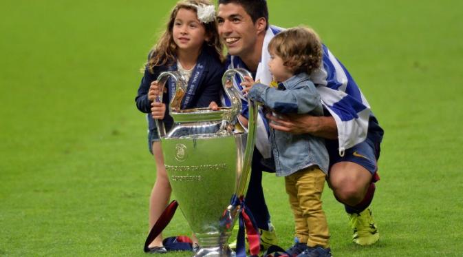 Luis Suarez bersama kedua anaknya merayakan keberhasilan Barcelona meraih trofi Liga Champions (OLIVER LANG / AFP)