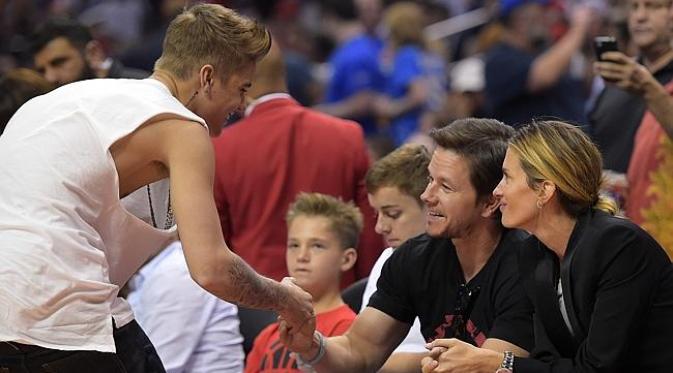 Justin Bieber saat menyapa Mark Wahlberg dan sang istri yang tengah menonton pertandingan basket [Foto:news.com.au]