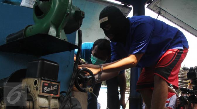 Seorang tersangka memasukan narkoba ke dalam mesin penghancur pada pemusnahan barang bukti tersebut di BNN, Jakarta, Rabu (17/6/2015). Sebanyak 18 kg sabu dan 622 butir ekstasi hasil pengungkapan BNN itu dimusnahkan. (Liputan6.com/Johan Tallo)