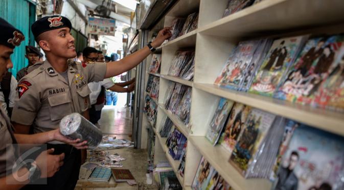Petugas memeriksa sejumlah VCD dan DVD bajakan saat melakukan razia di Plaza Glodok, Jakarta, Rabu (24/6). Razia dilakukan karena pabrik sekaligus tempat penjualan DVD terbesar di Jakarta itu masih beroperasi selama Ramadan. (Liputan6.com/Faizal Fanani)