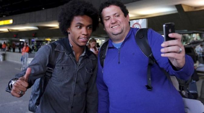 Willian mengacungkan jempolnya saat ber-selfie bersama fans di Bandara Internasional Guarulhos. REUTERS/Paulo Whitaker