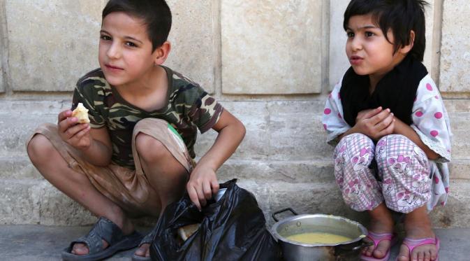 Anak-anak makan makanan gratis yang didistribusikan untuk Iftar, makanan setelah puasa, di masjid Abdul Khader al-Kilani di Baghdad, Irak,