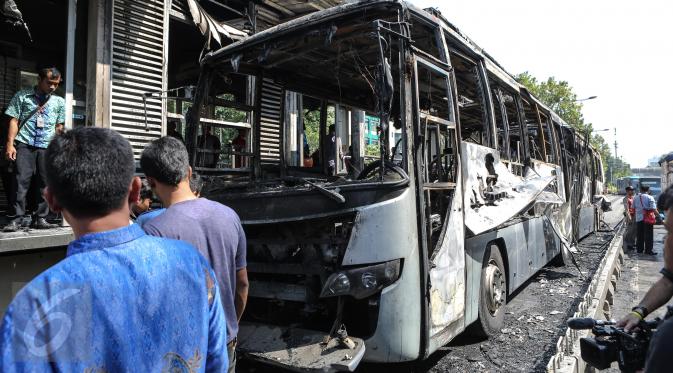Warga mengamati sisa Bus Transjakarta yang terbakar di Halte UI Salemba, Jakarta, Jumat (3/7). Bus Koridor V jurusan Ancol-Kampung Melayu tersebut terbakar sekitar pukul 08.30 WIB dan tidak menelan korban jiwa. (Liputan6.com/Faizal Fanani)