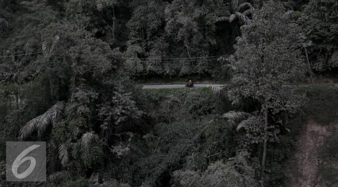 Pengendara melintas di jalan yang tertutup abu vulkanik erupsi Gunung Sinabung di Desa Sibintun, Sumatera Utara, Minggu (5/7/2015). Letusan yang terjadi dari 2013 sampai saat ini mengakibatkan puluhan ribu jiwa mengungsi. (Liputan6.com/Johan Tallo)