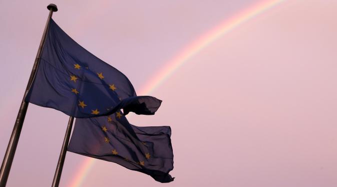 Sebuah pelangi terlihat di dekat bendera Eropa berkibar di Brussels, Belgia, (7/7/2015). (REUTERS/Francois Lenoir)