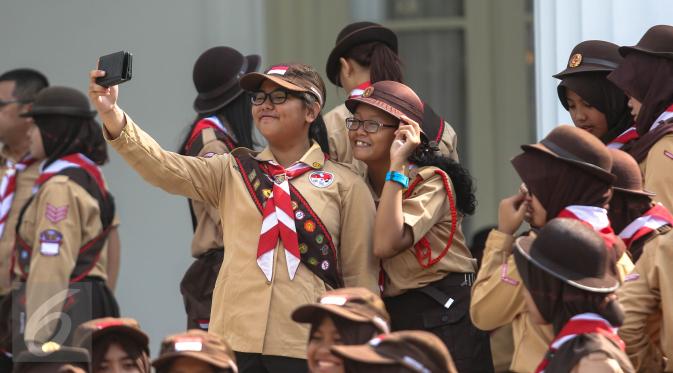 Seorang wanita dari delegasi gerakan Pramuka Indonesia tampak berselfie ria di Halaman Istana Merdeka, Jakarta, Jumat (24/7/2015). 462 kontingen Pramuka Indonesia yang akan mengikuti Jambore Pramuka Dunia ke-23. (Liputan6.com/Faizal Fanani)c
