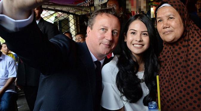 Dalam kunjungannya, David Cameron ditemani penyanyi cantik Maudy Ayunda. Mereka melakukan foto selfie bersama ibu pemilik warung. (via dailymail.co.uk)