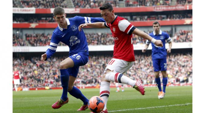 Pemain Everton, John Stones berusaha menghadang pemain Arsenal, Mesut Ozil pada pertandingan FA Cup di Emirates Stadium, Inggris, Sabtu (8/3/2015). (EPA/Tal Cohen)