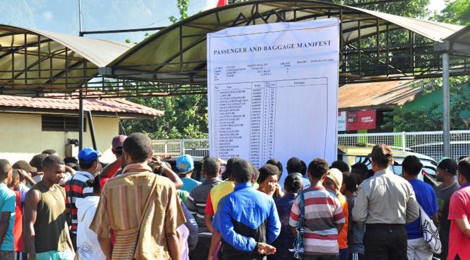 Sejumlah kerabat memeriksa manifes penerbangan yang dirilis di luar bandara Jayapura, Senin (17/8/2015). Pesawat Trigana Air yang membawa 54 penumpang tersebut  dinyatakan hilang usai lepas landas dari Jayapura. (AFP PHOTO / INDRAYADI THAMRIN)