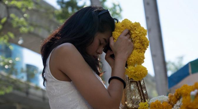 Seorang wanita berdoa di Kuil Erawan sebagai aksi simpatik atas ledakan bom pada Senin (17/8/2015) sekitar pukul 19.00 waktu setempat, Bangkok, Rabu (19/8/2015). Peristiwa tersebut dikabarkan telah menewaskan sekitar 20 orang. (AFP Photo/Jerome Taylor)