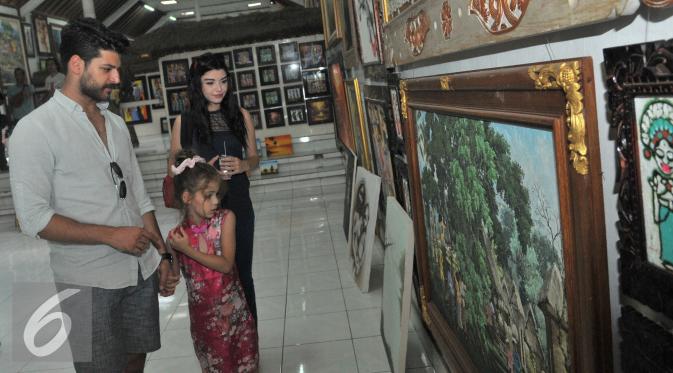 Pemain serial Elif, Emre Kivilcim (kiri) bersama Isabella Damla Guvenilir (tengah) dan Gulcin Tuncok (kanan)  melihat lukisan di Ubud Galeri kawasan Gianyar, Bali, Kamis (27/8/2015). (Liputan6.com/Herman Zakharia)