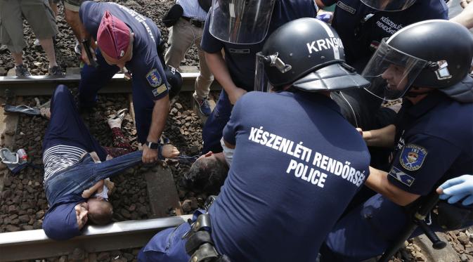 Keluarga pengungsi berbaring di jalur kereta di Hungaria. | via: Petr David Josek/Associated Press