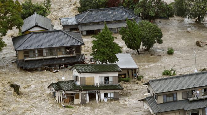 Warga yang terjebak luapan banjir dari Sungai Kinugawa di Joso, prefektur Ibaraki, menunggu dievakusi tim penyelamat, Jepang, Kamis (10/9). Satu orang hilang dan lebih dari 90 ribu warga diperintahkan untuk mengungsi. (REUTERS/Kyodo)