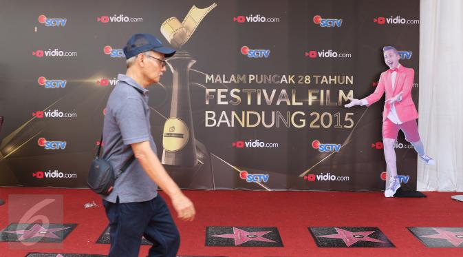 Seorang pria berjalan melintasi banner Festival Film Bandung (FFB) 2015 yang terpasang di Monumen Perjuangan Rakyat, Bandung, Sabtu (12/9/2015). (Liputan6.com/Herman Zakharia)